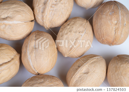 Scattered shells of walnuts suggest chef preparing delicious recipes. Warm ambient light highlights textured shells of walnuts arranged for cooking and snacking Scattered shells of walnuts suggest chef preparing delicious recipes. Warm ambient light highlights textured shells of walnuts arranged for cooking and snacking 137824503