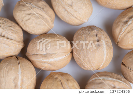 Closeup of walnuts showcasing surface textures and colors. Photograph capturing unshelled walnuts highlighting textured surfaces and natural brown color tones in studio setting Closeup of walnuts showcasing surface textures and colors. Photograph capturing unshelled walnuts highlighting textured surfaces and natural brown color tones in studio setting 137824506