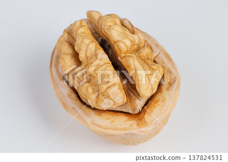 Walnut closeup detail. Photograph emphasizing intricate grooves on walnut shell surface. Studio shot highlighting fine textures and patterns of walnut kernel in shell Walnut closeup detail. Photograph emphasizing intricate grooves on walnut shell surface. Studio shot highlighting fine textures and patterns of walnut kernel in shell 137824531