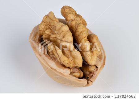 Detailed view showcasing folds and shadows around walnut kernel. Closeup image features curved structures and warm hues of walnut kernel with soft shadows and clear focus Detailed view showcasing folds and shadows around walnut kernel. Closeup image features curved structures and warm hues of walnut kernel with soft shadows and clear focus 137824562