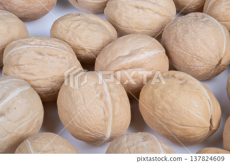 Walnuts on counter. Warm light highlights scattered nuts on rustic kitchen surface. Cashew shells and walnuts arranged on countertop evoke traditional cooking ambiance Walnuts on counter. Warm light highlights scattered nuts on rustic kitchen surface. Cashew shells and walnuts arranged on countertop evoke traditional cooking ambiance 137824609