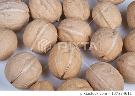 Repeated walnut shell design pattern. Earthtoned graphic background featuring walnut textures. Pattern showcasing repeating walnut shells with shadows and natural tones 137824611
