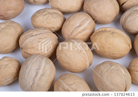 Arranged walnuts on smooth white background. Arrangement of uniformly spaced walnut shells on flawless white backdrop with soft illumination for product presentation 137824613