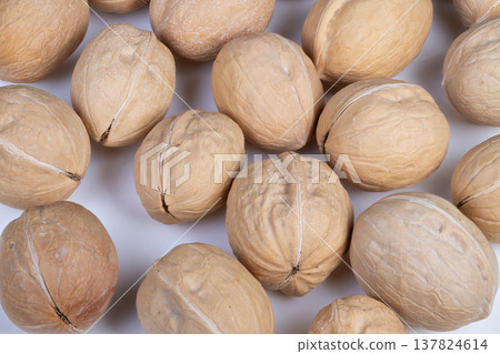 Closeup cluster of walnuts in shells on white backdrop, natural brown tones, shallow depth of field, rough shell texture, food styling for snack and ingredient photography Closeup cluster of walnuts in shells on white backdrop, natural brown tones, shallow depth of field, rough shell texture, food styling for snack and ingredient photography 137824614