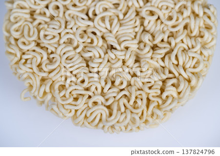 Uncooked instant noodles disk with detailed curly structure, neutral background and shallow depth of field emphasize starch strands, useful for ingredient and manufacturing visuals Uncooked instant noodles disk with detailed curly structure, neutral background and shallow depth of field emphasize starch strands, useful for ingredient and manufacturing visuals 137824796