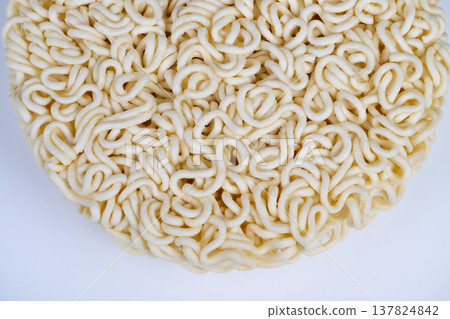 Closeup round instant noodles block showing tight curly strands, crisp dry texture on clean white background, studio lighting highlights delicate pale surface and circular form Closeup round instant noodles block showing tight curly strands, crisp dry texture on clean white background, studio lighting highlights delicate pale surface and circular form 137824842
