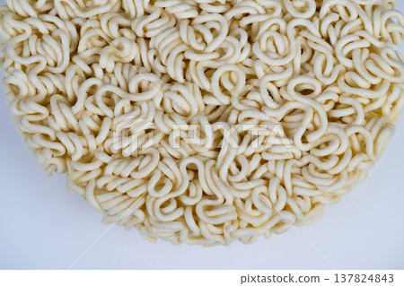 Closeup captures intricate curly ramen strands. Detailed macro photography showcasing coiled ramen noodles with textured surface and shadow patterns for analysis 137824843