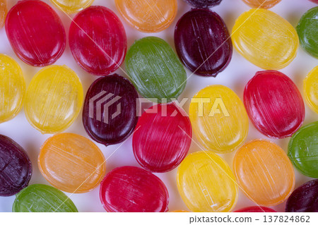 Bright multicolored sweets with reflections. Vivid multihued confectionery displaying shine and texture. Dramatic macro shot of colorful candies highlighting sugar and shine 137824862