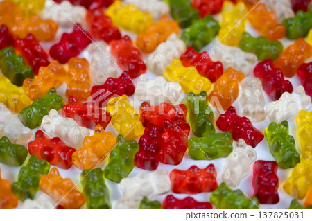 Vibrant gummy bears resting on fluffy marshmallow bed for festive decor. Cheerful and colorful gummy bears laid on marshmallow cushion creating seasonal gift appeal 137825031