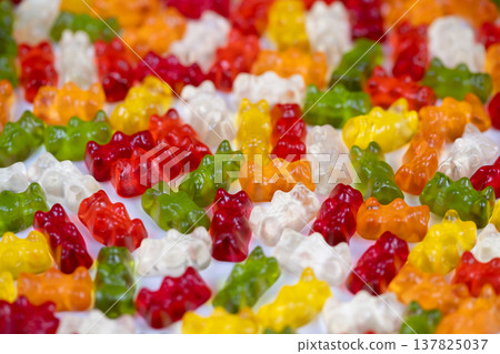 Festive assortment of gummy bears adds cheer to event displays. Playful multicolored gummy bears scattered to evoke happiness and festive spirit for celebrations Festive assortment of gummy bears adds cheer to event displays. Playful multicolored gummy bears scattered to evoke happiness and festive spirit for celebrations 137825037