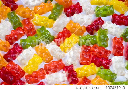 Closeup of vibrant gummy bears. Macro shot emphasizing glossy translucent gummy textures. Highresolution view highlighting refraction in multicolored gelatin candies 137825043