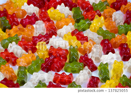 Top view of translucent multicolored gummy bears piled together, light passing through jelly surfaces, high contrast colors for gourmet candy editorial and product detail shots Top view of translucent multicolored gummy bears piled together, light passing through jelly surfaces, high contrast colors for gourmet candy editorial and product detail shots 137825055