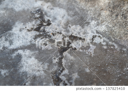 Abstract depiction of frosted ice showing subtle shadowing and cool tones. Detailed abstract image of cracked granular ice featuring shadow effects and cool gray hues 137825410