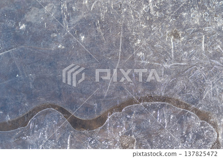 Ice melting detailed. Frozen ice with dark winding channel and frost texture. Detailed closeup of melting ice with twisting dark channel and shimmering frost surface 137825472