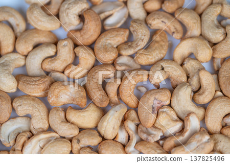 Roasted cashews perfect for cooking. Warm kitchen ambiance with detailed food presentation visuals. Enjoy lightly toasted cashews suitable for culinary creations and menu displays 137825496
