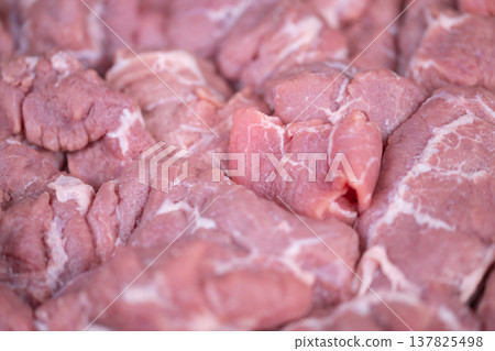 Meat preparation process. Cooking setup with sliced pork. Chef arranging tender pork slices methodically. Orderly placement of pork slices indicates organized kitchen workflow Meat preparation process. Cooking setup with sliced pork. Chef arranging tender pork slices methodically. Orderly placement of pork slices indicates organized kitchen workflow 137825498