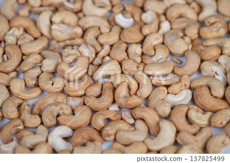 Evenly roasted cashew presentation. Display of uniformly roasted cashews on tray. Commercial showcase featuring generous quantity of roasted cashews arranged neatly Evenly roasted cashew presentation. Display of uniformly roasted cashews on tray. Commercial showcase featuring generous quantity of roasted cashews arranged neatly 137825499