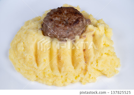Traditional rustic presentation of meat and mashed side dish. Warmtoned rustic display featuring sliced cutlet and smooth mashed accompaniment in minimal background Traditional rustic presentation of meat and mashed side dish. Warmtoned rustic display featuring sliced cutlet and smooth mashed accompaniment in minimal background 137825525
