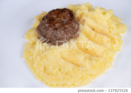 Grilled cutlet on creamy mash. Single piece of meat with textured potato mash presentation. Elegant meat cut placed on white plate with textured mashed potatoes underneath 137825526