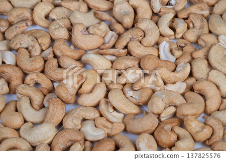 Sunlit farmstead cashew kernels drying. Natural light illuminates freshly dried cashew kernels on mesh. Farmhouse environment with sun drying cashew kernels on mesh surface 137825576