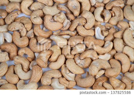 Roasted nut closeup. Tightly cropped photo showing salted roasted cashew nuts texture. Detailed view of seasoned roasted cashew nuts with salt crystals and warm ambiance Roasted nut closeup. Tightly cropped photo showing salted roasted cashew nuts texture. Detailed view of seasoned roasted cashew nuts with salt crystals and warm ambiance 137825586
