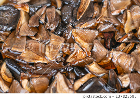 Detailed view of dried mushrooms. Close examination of rehydrated mushroom slices. Detailed closeup capturing moist and rehydrated characteristics of dried mushroom pieces Detailed view of dried mushrooms. Close examination of rehydrated mushroom slices. Detailed closeup capturing moist and rehydrated characteristics of dried mushroom pieces 137825593