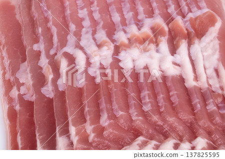 Stylish bacon stacking for photography. Artistic display of raw bacon for food styling photos. Elegant layered raw bacon slices arranged to enhance culinary visual appeal 137825595