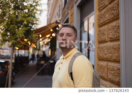 Man with backpack standing on evening city street Man with backpack standing on evening city street 137826143