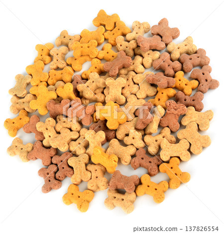 Large pile of colorful bone-shaped dog biscuits isolated on a white background. Top view of various crunchy pet treats in brown, yellow, and beige shades for canine nutrition and training rewards. 137826554