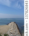A stone breakwater stretching vertically across the sandy beach and calm sea. 137826843