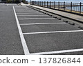 A parking lot along the Japanese coast with a fence and a view of the sea. 137826844