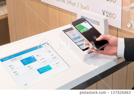 The hands of a user making a smartphone payment at a self-checkout counter. 137826863