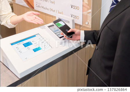 The hands of a customer making a cashless payment and the store clerk assisting them. 137826864