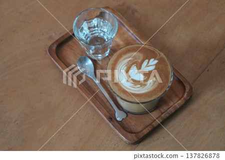 top view beautiful brown and white layer coffee  in low glass on wooden tray, silver spoon and water in glass, brown wooden floor background, drink, cool, food, copy space 137826878