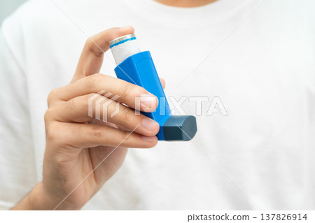 Asthma and chronic obstructive pulmonary disease COPD, Asian young man using metered dose inhaler MDI. 137826914