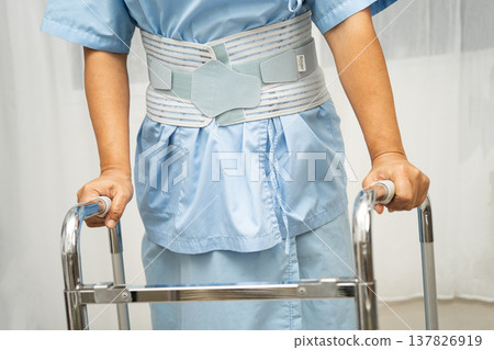 Asian senior pain back wearing elastic support belt with walker. Asian senior pain back wearing elastic support belt with walker. 137826919