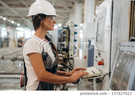 Side view of machine operator. Woman is in the window making factory Side view of machine operator. Woman is in the window making factory 137827022