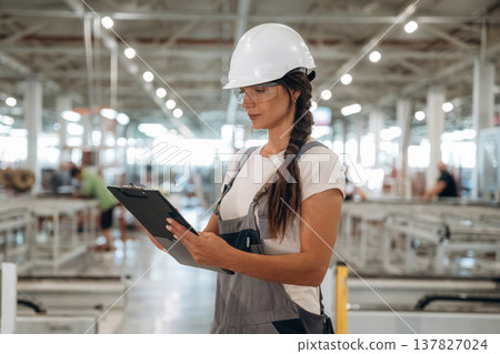 Female engineer is with notepad. Woman is in the window making factory 137827024