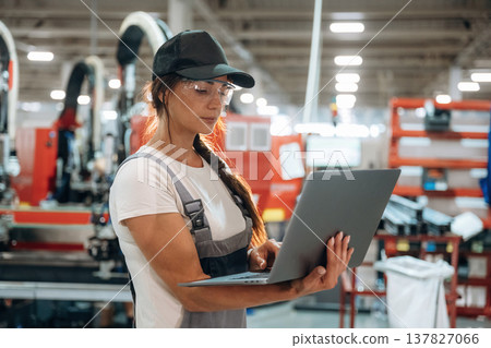 Laptop is in hands. Woman is in the window making factory Laptop is in hands. Woman is in the window making factory 137827066