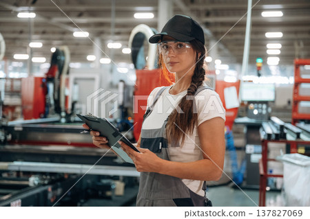 Notepad is in hands. Woman is in the window making factory 137827069