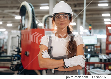 In white hardhat. Woman is in the window making factory In white hardhat. Woman is in the window making factory 137827078