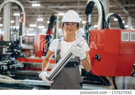 Quality product, plank in hands. Woman is in the window making factory 137827092