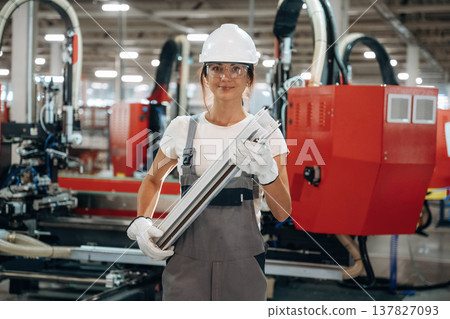 Quality product, plank in hands. Woman is in the window making factory 137827093