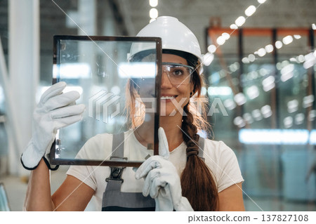 In gloves, holding little frame with glass. Woman is in the window making factory In gloves, holding little frame with glass. Woman is in the window making factory 137827108