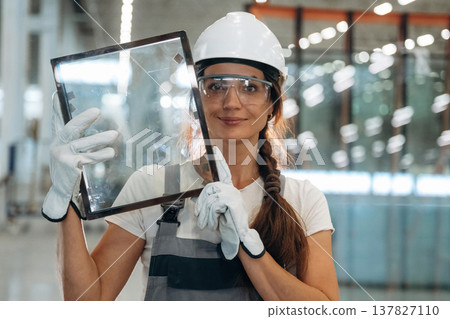 In gloves, holding little frame with glass. Woman is in the window making factory In gloves, holding little frame with glass. Woman is in the window making factory 137827110