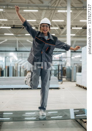 Testing toughness of the glass. Woman is in the window making factory Testing toughness of the glass. Woman is in the window making factory 137827127