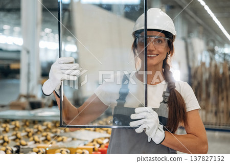 Little glass in hands. Woman is in the window making factory 137827152