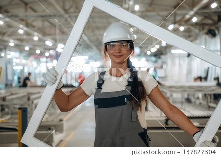 Big frame in hands. Woman is in the window making factory Big frame in hands. Woman is in the window making factory 137827304
