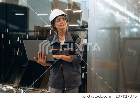 In gray uniform, with laptop. Woman is in the window making factory 137827379