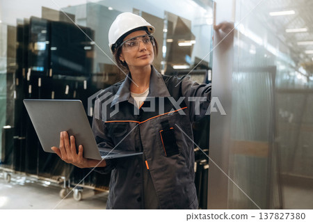 In gray uniform, with laptop. Woman is in the window making factory 137827380